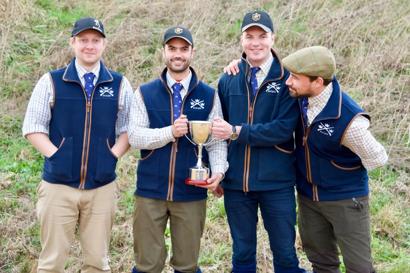 Four members in club gilets holding a trophy